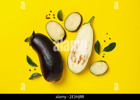 Fresh raw eggplants with water drops on yellow background Stock Photo
