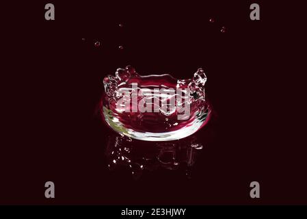water splash isolated on dark red. fresh clean transparent drinking water splash. Stock Photo