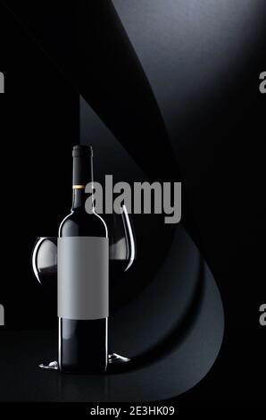 Bottle and glasses of red wine on a black background. Bottle with the empty label, saved clipping path for a label. Stock Photo