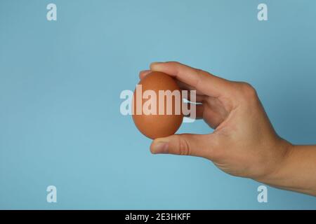 Female hand hold boiled egg on blue background Stock Photo