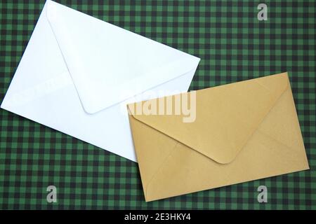 White and beige envelopes and on a green checkered background. Blank template Stock Photo