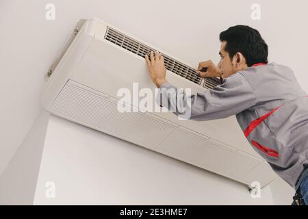 Air conditioner repairers are checking and repair air hanging on the wall. Stock Photo