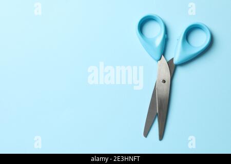 Blue scissors on blue background, space for text Stock Photo