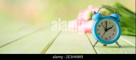 Spring time daylight saving concept - with alarm clock and flowers Stock Photo