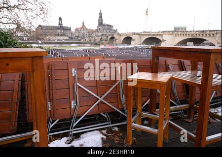 Dresden, Germany. 19th Jan, 2021. Folded tables and chairs stand at a closed beer garden against the backdrop of Old Town. In the context of the upcoming Corona consultations of the federal government and the states, among other things, an extension of the lockdown until mid-February is being discussed. Credit: Sebastian Kahnert/dpa-Zentralbild/dpa/Alamy Live News Stock Photo