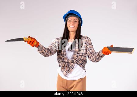 A woman in a working uniform and with building materials poses on a white background with side space. Stock Photo