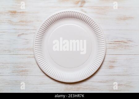 Disposable eco paper plate on wood background. Eco-friendly, plastic-free tableware. Organic plate made of environmental material. Copy space. Top vie Stock Photo