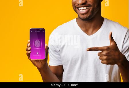 Black Man Pointing At Cellphone With Fingerprint Scanner, Yellow Background Stock Photo