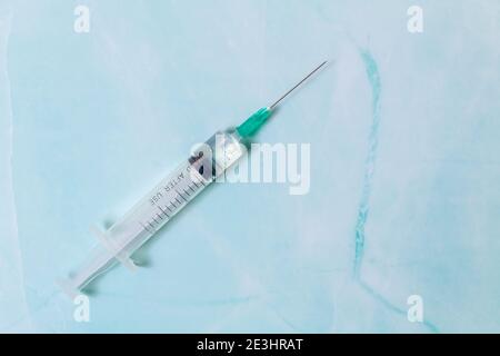 Close-up of medical syringe on blue background with copy space. Disposable injection syringe with vaccine. Syringe filled with liquid. Minimal medicat Stock Photo