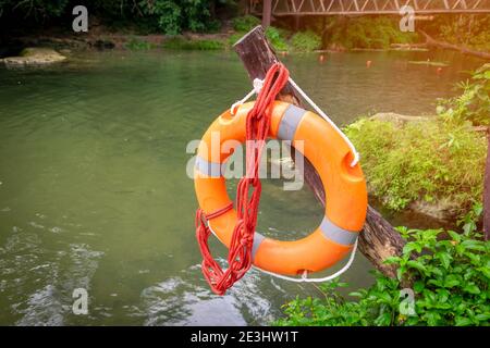 A rubber ring with a rope hanging on a wooden pole along the river was prepared for rescue. Stock Photo