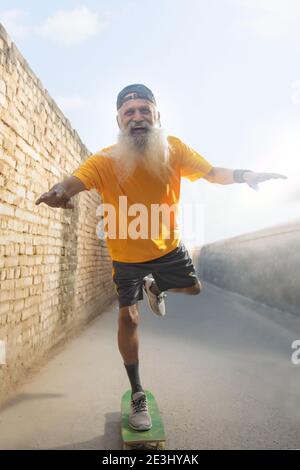 A BEARDED OLD MAN CHEERFULLY POSING WHILE CYCLING Stock Photo