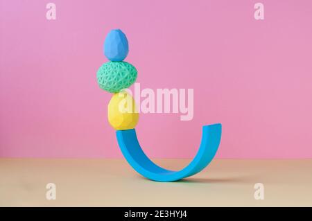 Easter minimalistic decor concept. Geometric Easter eggs standing on top of each other on pink background with blank space for text. Stock Photo
