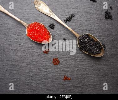 caviar of paddlefish fish and red chum salmon caviar in a spoon, black background, top view Stock Photo