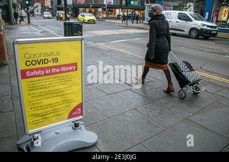 WIMBLEDON  LONDON, UK  19 January 2021.  Pedestrians walk past a sign outside a public library in Wimbledon town centre for visitors to follow the coronavirus safety measures. Credit: amer ghazzal/Alamy Live News Stock Photo