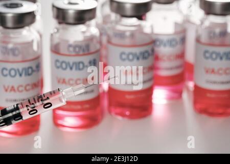 The needle of syringe closeup on blurred vaccine vials to fight the of Covid-19 Stock Photo