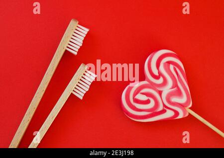 Festive red background. Sweet heart shaped candy. And two toothbrushes like a symbol of love. Valentine's Day. 14 of February. Ideas of gifts. Flat la Stock Photo