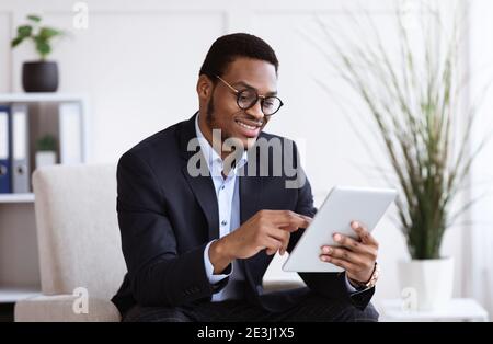 Happy african american young businessman using digital tablet in office Stock Photo