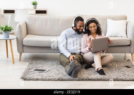 Black man and woman having videocall using laptop waving hand Stock Photo