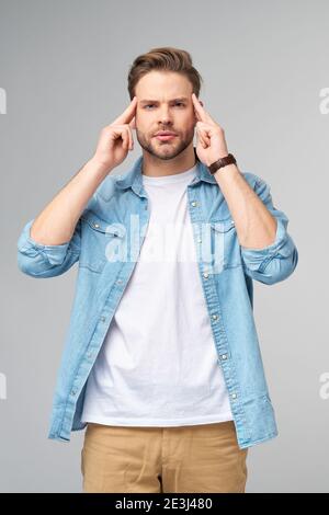 Young caucasian man massaging temples trying to calm down reducing stress Stock Photo