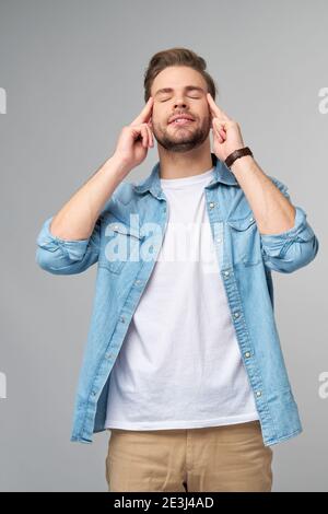 Young caucasian man massaging temples trying to calm down reducing stress Stock Photo