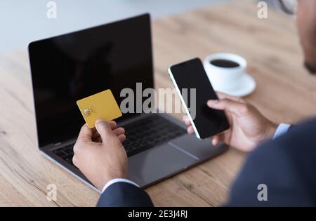 Black businessman using smartphone and laptop with empty screens Stock Photo