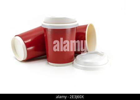 Close up red disposable paper cups or takeaway cup for hot drinks with lid on white background, one stand as usual and the others tilted to lie down o Stock Photo