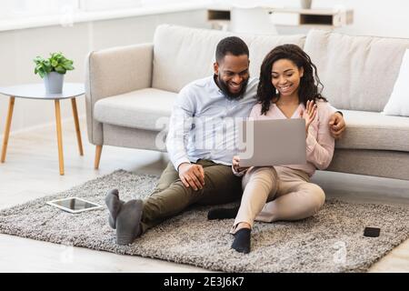Black couple having videocall using laptop waving hands Stock Photo