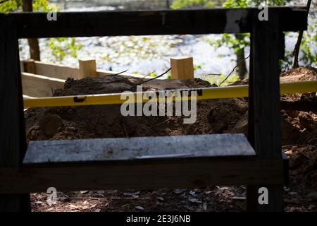 Workman's scaffold and yellow caution tape in front of a mound of dirt Stock Photo