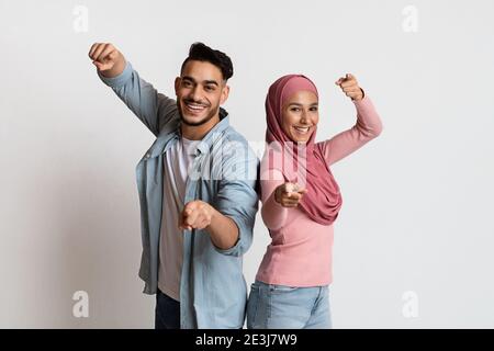 Gotcha. Cheerful Muslim Couple Pointing Fingers At Camera, Indicating Somebody Stock Photo