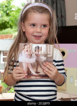 Young girl holding up a photograph of a child ballerina Stock Photo