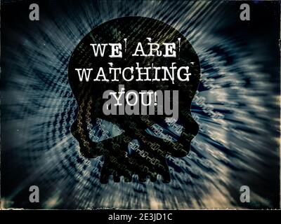 We Are Watching You! text written across Black Skull on Binary code blue background on a vintage distressed looking computer digital display screen Stock Photo