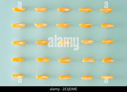 Creative pattern with peeled  orange slices of tangerine  on vibrant  blue background. Minimal  flat lay. Stock Photo