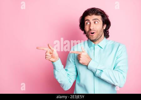 Photo portrait of surprised man pointing two fingers at blank space isolated on pastel pink colored background Stock Photo