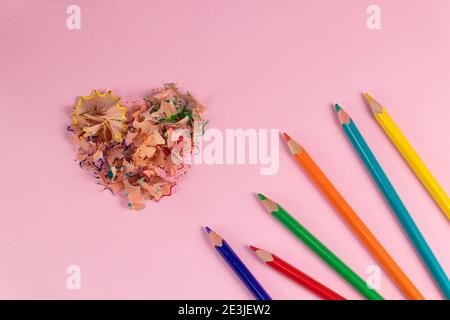 Sharpened colored pencils and heart-shaped pencil shavings. Decoration for St. Valentine's Day. Top view Stock Photo