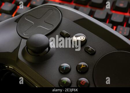 Steam controller on a red illuminated gaming keyboard. Stock Photo