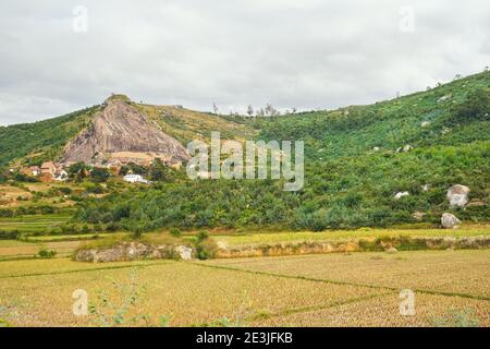 Typical landscape of Madagascar on overcast cloudy day - people working at wet rice fields in foreground, houses on small hills near Antananarivo Stock Photo