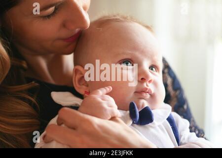 Young mother with her baby son, detail on heads close together, as she's about to kiss him on head Stock Photo