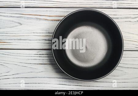 Black clay bowl on a wooden table. View from above Stock Photo