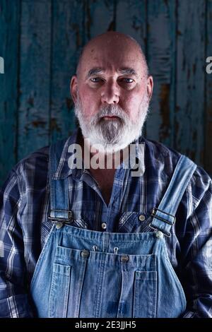 Portrait of an elderly man in bib overalls. Stock Photo