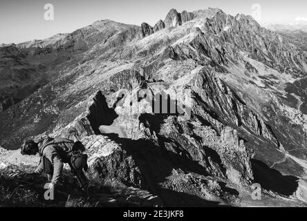 Alpinist preparing to descend from Le Brevent mountain in summer and Alpine landscape at background. Chamonix, Mont Blanc, Savoie, France. Black white Stock Photo