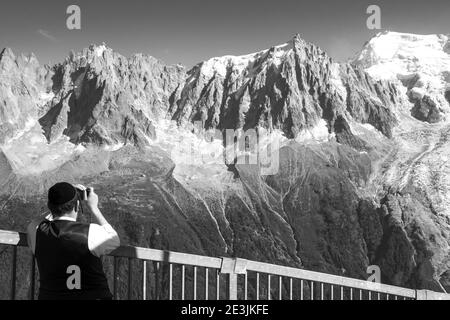 Orthodox Jew man admiring and taking photo of snow cover Mont Blanc mountain. French Alps summer trip vacation. Chamonix, Savoie, France. Black white. Stock Photo