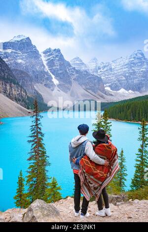 The beautiful Lake moraine at sunset, Beautiful turquoise waters of the Moraine lake with snow-covered rocky mountains in Banff National Park of Canada , couple visit the lake men and woman mid age Stock Photo