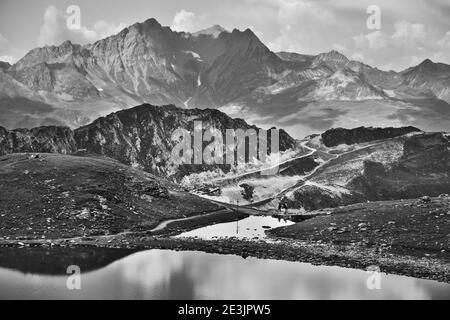 Unrecognizable couple hiking between lakes at French Alps near Arcs 2000 ski station. Summer in Savoie, France. Black and white photo. Stock Photo