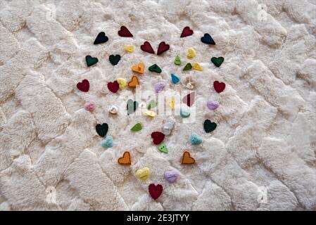 Multi-colored heart design on a soft white blanket.  Design is mostly made from heart shaped buttons. Stock Photo