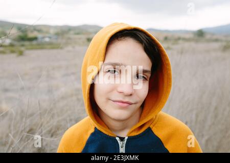 Portrait Of A Boy Wearing An Orange Hoodie outside In Nature Stock Photo