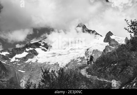 Father and son hiking in French Alps in summer. The Aiguille des Glaciers, mountain in the Mont Blanc massif. Savoie, France. Black white photo Stock Photo