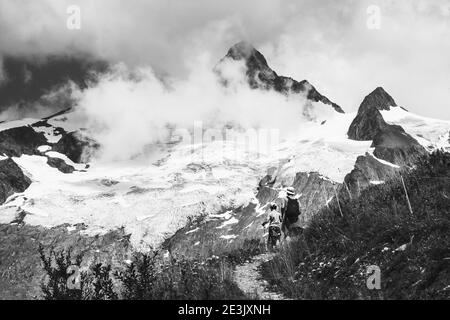 Father and son hiking in French Alps in summer. The Aiguille des Glaciers, mountain in the Mont Blanc massif. Savoie, France. Black white photo Stock Photo