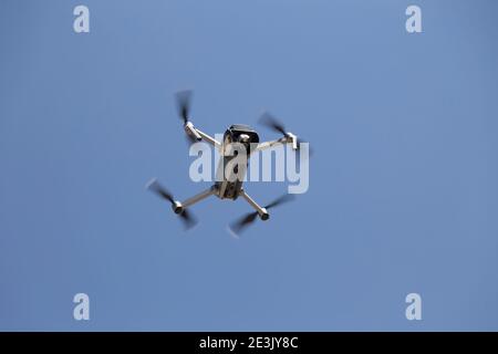 Drone flying overhead in cloudy blue sky. Close-up. Stock Photo