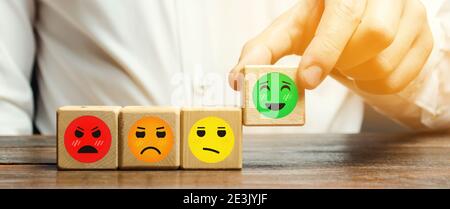 One block with a positive face stands out from the rest of the negative emotions. Concept of good rating, review and feedback. Satisfied customers. Stock Photo