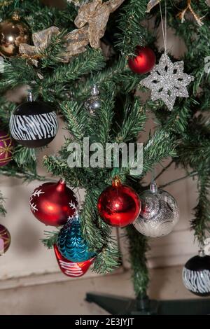 Black, silver, red, purple, and blue globe ornaments next to a red dove, a clear star ornament, and gold and white ribbon on an artificial Christmas t Stock Photo